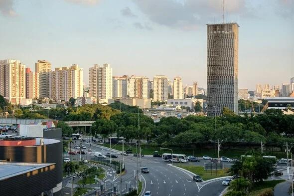 Vista da cidade de São Bernardo do Campo com prédios ao fundo enquanto carros passam por uma rua