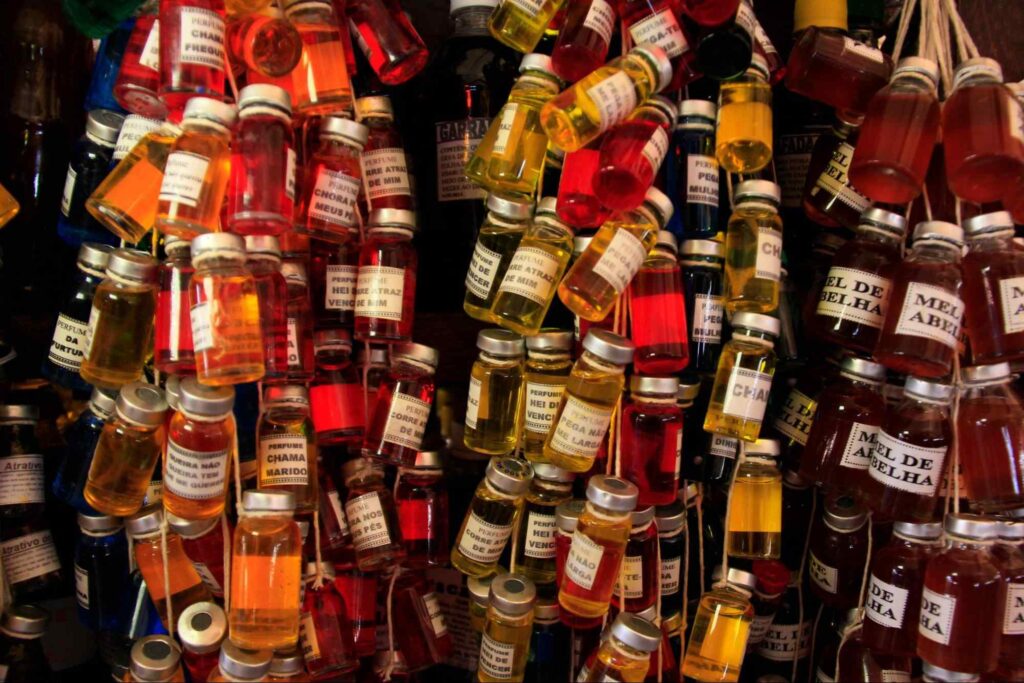 Frascos multicoloridos pendurados em um cordão, expostos no Mercado Ver-o-Peso. O conteúdo das pequenas ampolas vai de uma coloração avermelhada até o laranja e azul.