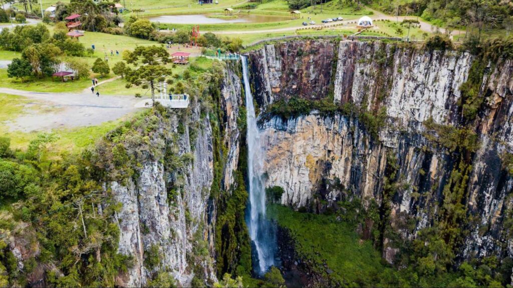 A água despenca em um fluxo único pelos grandes paredões na Cachoeira do Avencal, cuja superfície varia entre branco, cinza e preto.